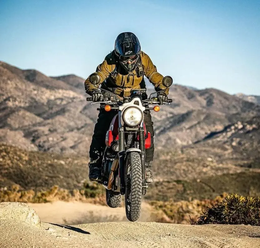 Motociclista de aventura saltando en moto por montañas