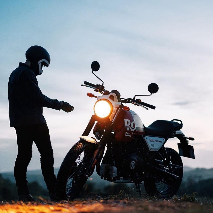 Motociclista junto a su moto al atardecer
